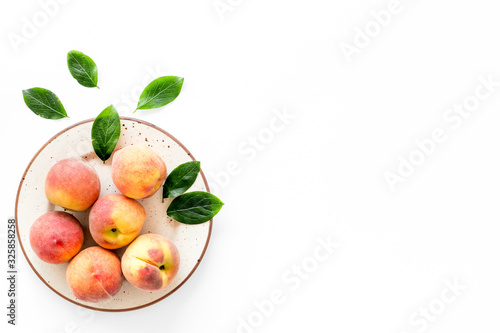 Summer fruits. Ripe red peaches on plate on white table top-down copy space