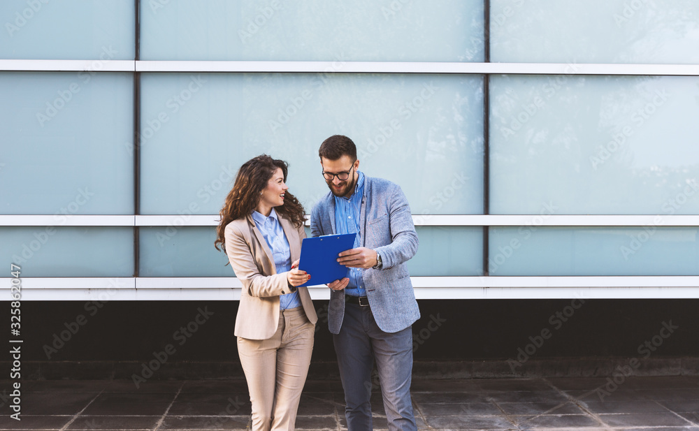 Businessman and business woman with clipboard discussing about business project