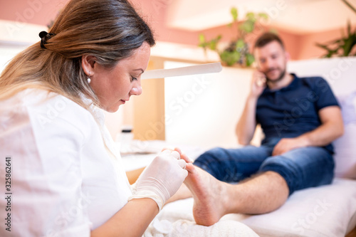 Pedicure spa worker taking care of her clients feet