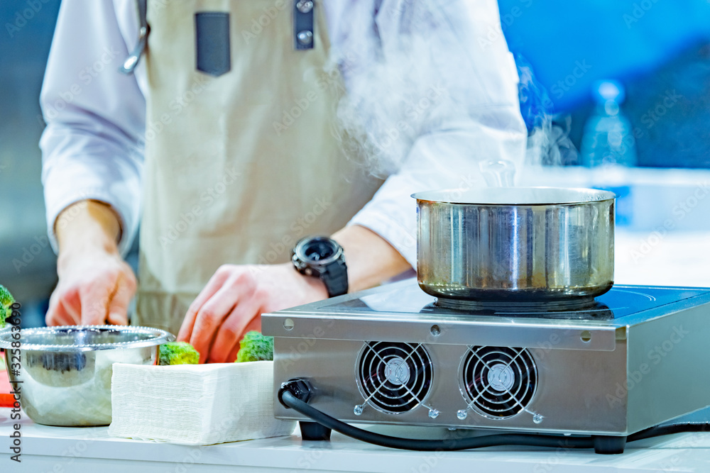 The chef prepares a broccoli. Vegetable side dishes in the restaurant menu. Vegetarian food. Ladle with boiling water close-up. Heat treatment of products. Cooking vegetables. The chef prepares a broccoli. Vegetable side dishes in the restaurant menu. Vegetarian food. Ladle with boiling water close-up. Heat treatment of products. Cooking vegetables.