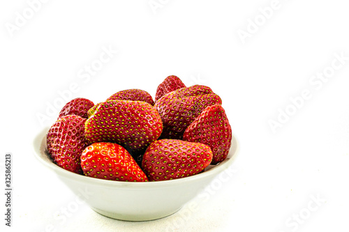 red strawberry berries in a plate on a white background, space for text