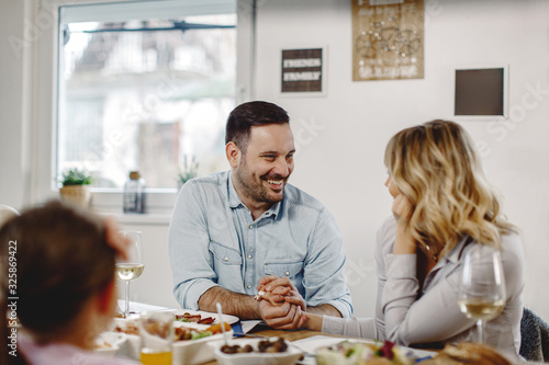 Loving couple holding hands and talking while having lunch in dining room.