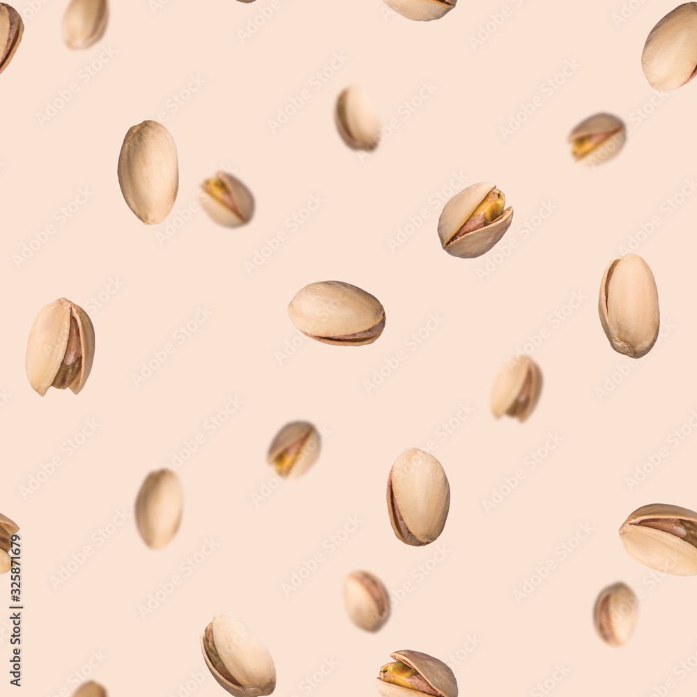 Seamless pattern with falling pistachio nuts on beige background