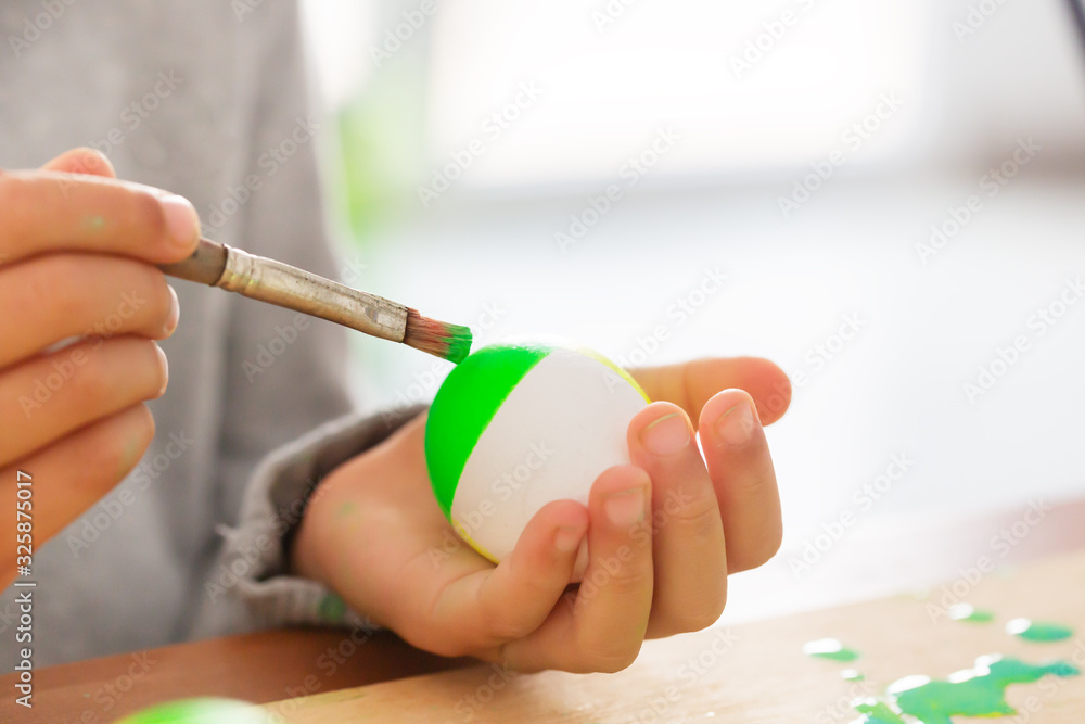 Boy in his room paints easter eggs with a brush Boy in his room paints easter eggs with a brush
