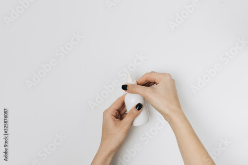 Cropped shot of woman with hands and bottle of lotion isolated on white