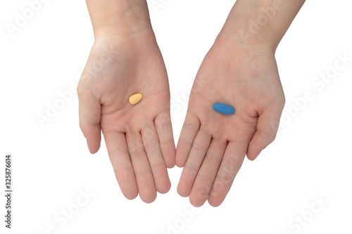 Young woman's hands offering blue and brown pills isolated on white background photo