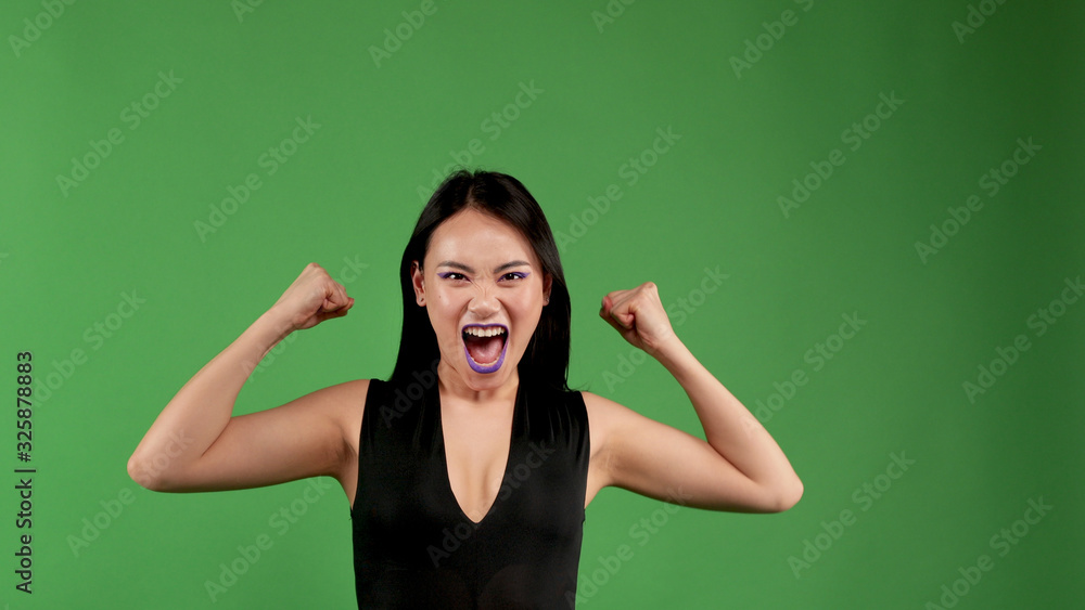 Actively aggressive young woman raising her arms up showing her biceps Actively aggressive young woman raising her arms up showing her biceps