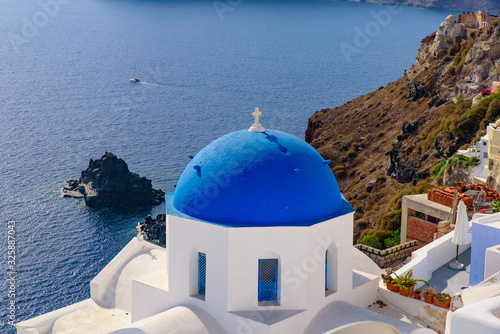 Blue domed church and traditional white houses facing Aegean Sea in Oia, Santorini, Greece