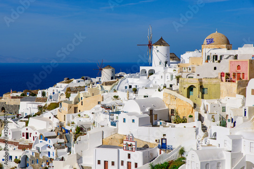 Windmill and traditional white buildings facing Aegean Sea in Oia, Santorini, Greece