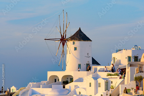 Windmill and traditional white buildings in sunset light in Oia, Santorini, Greece