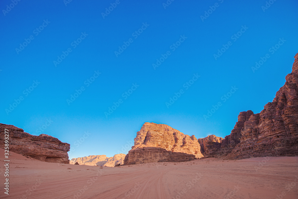 Textured sand mountains of red and orange sand against the blue sky, Jordan, Wadi Rum desert.