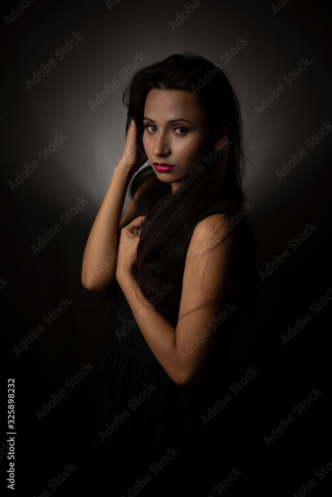 Fashion portrait of young and attractive Indian Bengali brunette girl in black western dress in front of black studio background. Indian lifestyle. Fashion portrait of young and attractive Indian Bengali brunette girl in black western dress in front of black studio background. Indian lifestyle.