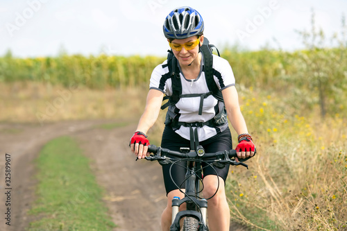 Beautiful girl cyclist rides on the field on a bicycle. Healthy lifestyle and sport. Leisure and hobbies