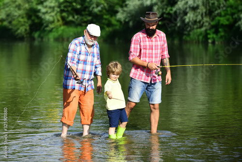 Fishing. Little boy fly fishing in river with his father and grandfather.