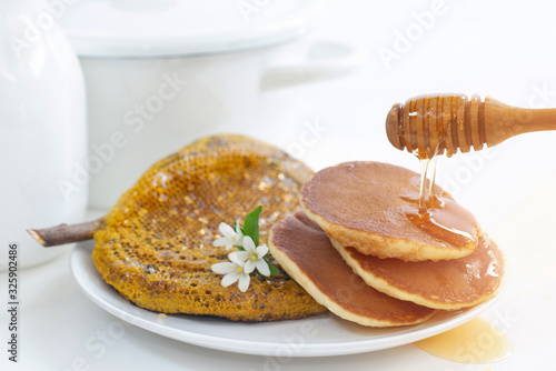 White flowers or Orange jasmine with stack of pancakes on white background, honey dripping from dipper stick on pancakes photo