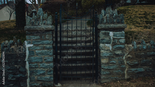 A Closed Black Metal Gate With a Path Behind  Leading up to an Estate Like Home