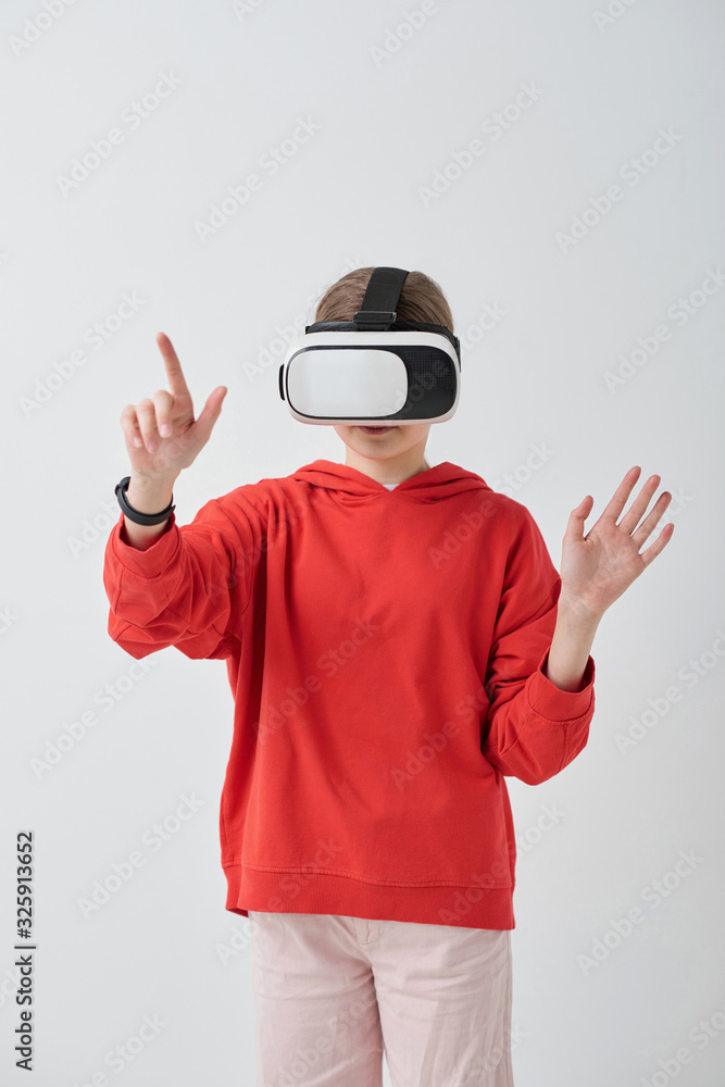 Fototapeta premium School girl in red hoodie using virtual reality simulator while solving task in educational video game