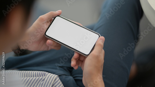 Εκτύπωση καμβά Close up view of male entrepreneur holding horizontal smartphone while lying rel