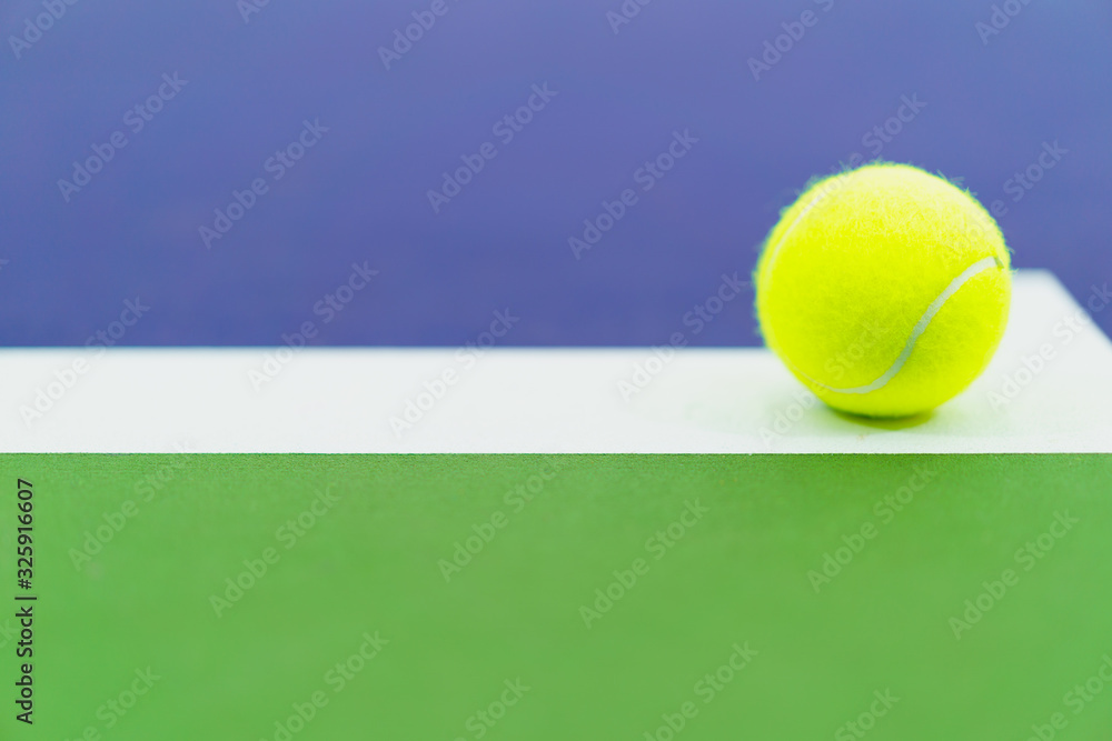 one new tennis ball on white line in blue and green hard court, copy space on left