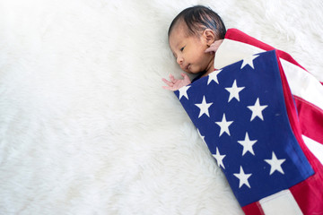 Asian newborn baby in American flag blanket, celebrating 4th July independence day