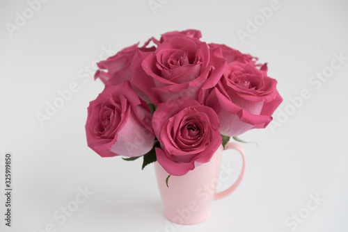 Bouquet of pink roses on a light background. A bouquet of flowers stands in a pink mug. Pink vase.