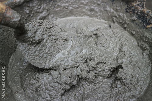 close up on fresh wet mixed cement mortar with trowel inside bucket photo