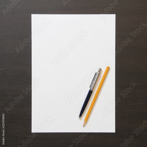Template of white paper with pen and pencil on dark wenge color wooden background.