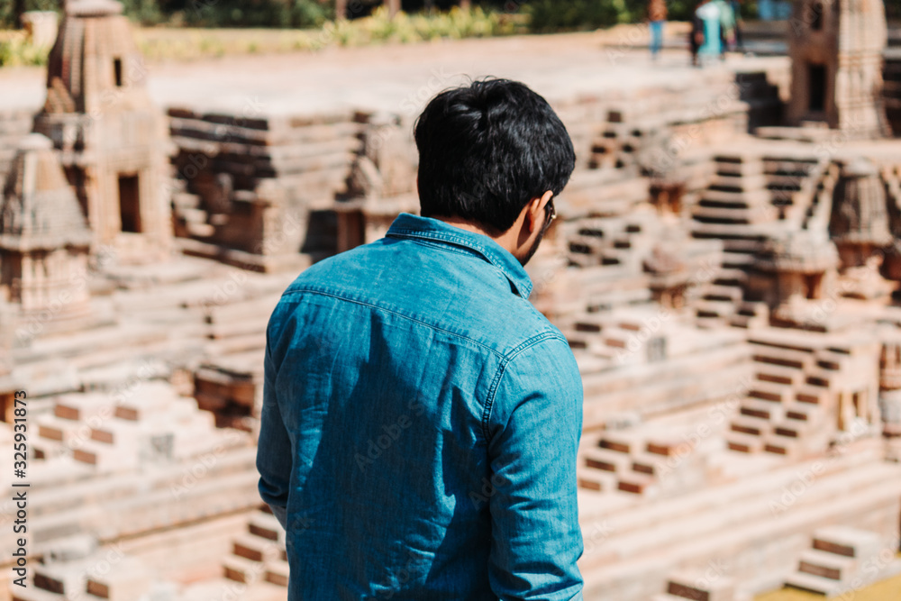 Indian man standing in front of the step well at the Sun Temple in Modhera, Gujarat, India