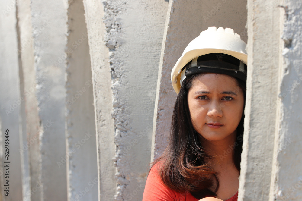 Female civil engineer or architect wear the white helmet sitting in the large cement pipes stacked. Female civil engineer or architect wear the white helmet sitting in the large cement pipes stacked.