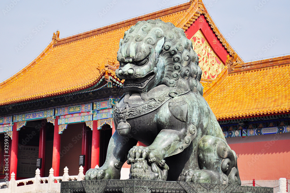 Naklejka premium Chinese architecture in Beijing, a Chinese traditional lion with a mustache on the background of a yellow old roof with tiles