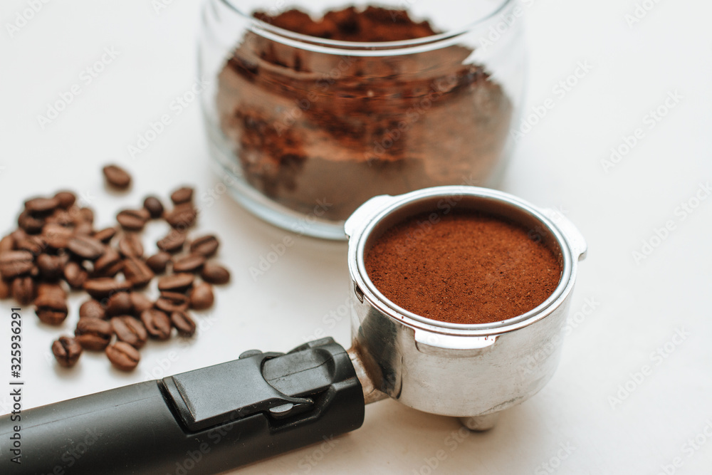 Fototapeta premium coffee horn with natural ground coffee and ground coffee in a glass jar on a white background