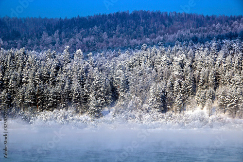 In the background, on the other bank of the river, conifer winter forest begins. Everything is simple, beautiful and expressive. In the foreground - mist rising from the water.