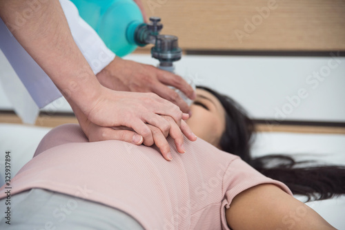 Hands of doctors giving cardiac massage and resuscitation to a female patient in the emergency room