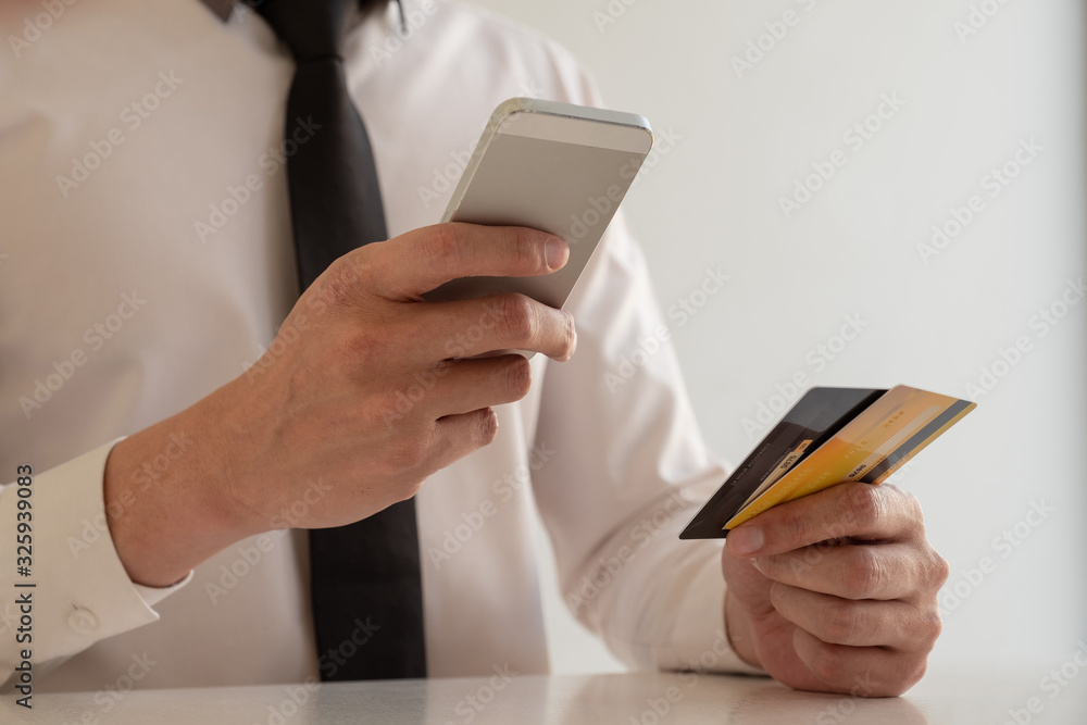 The hands of business people holding credit cards and smartphones for online shopping and paying via the internet The hands of business people holding credit cards and smartphones for online shopping and paying via the internet