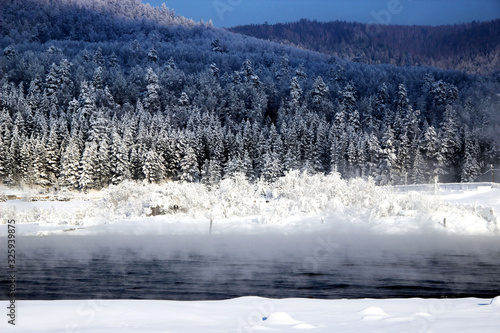 In the background, on the other bank of the river, conifer winter forest begins. Everything is simple, beautiful and expressive. In the foreground - mist rising from the water and fluffy snow. © Pavel