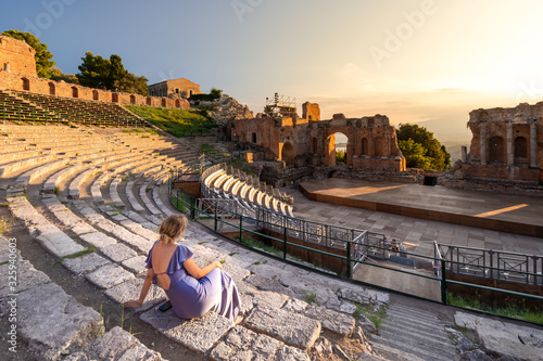 Wallpaper Mural A woman dressed in purple beholds a dramatic sunset at the Greek Theater in Taormina, Sicily Torontodigital.ca