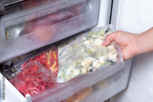 Freezer and frozen vegetables, a person taking food from the freezer photo