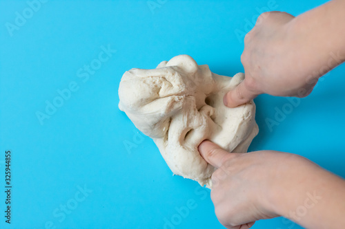 Salt dough for modeling in the hands of a child on a blue background