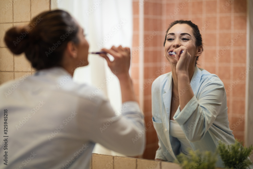 Reflection in a mirror of happy woman brushing teeth in the morning. Reflection in a mirror of happy woman brushing teeth in the morning.