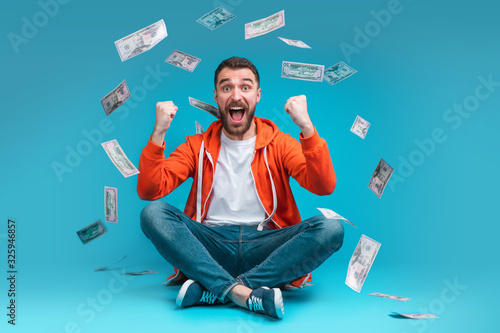 Young attractive bearded man celebrating victory after betting at bookmaker's website photo