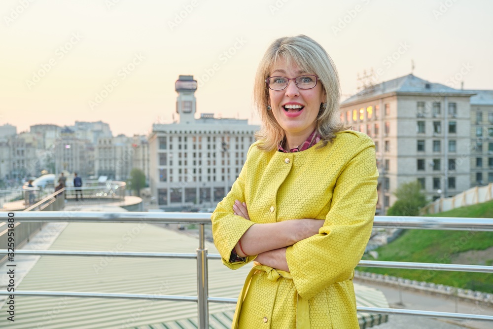 Outdoor portrait of smiling mature woman with folded hands