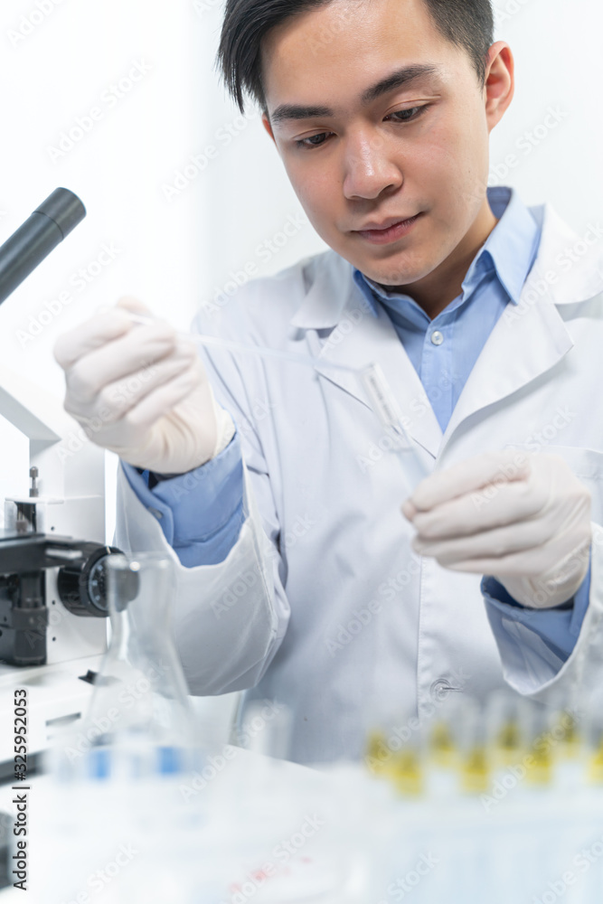 Concentrated brunette male person looking at test tube Concentrated brunette male person looking at test tube
