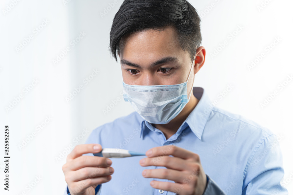 Attentive young male person staring at thermometer Attentive young male person staring at thermometer