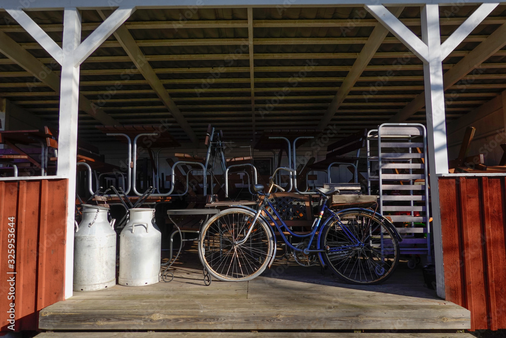 Naklejka premium Grisslehamn, Sweden S bicycle and summer furniture tucked away on a porch on a farm.
