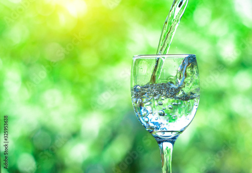 Pour water into a glass of water and bubble with the natural background. copy space