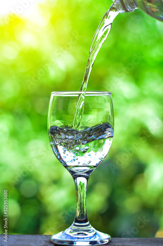 Pour water into a glass of water and bubble with the natural background.