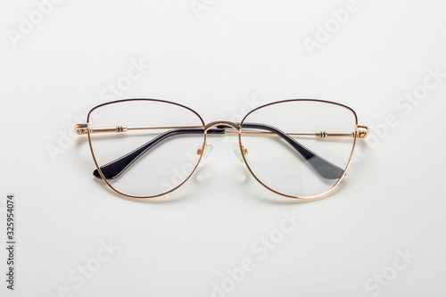 The golden female medical eyeglasses with folded temples on a white background