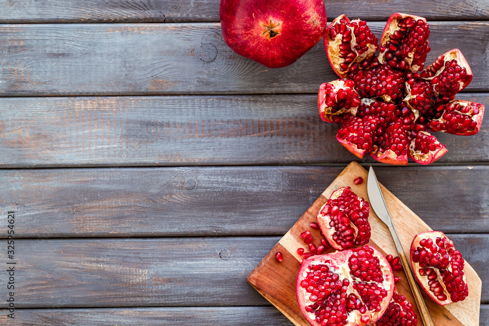 Peel pomegranate. Open fruit on cutting board on dark wooden background top-down copy space Peel pomegranate. Open fruit on cutting board on dark wooden background top-down copy space