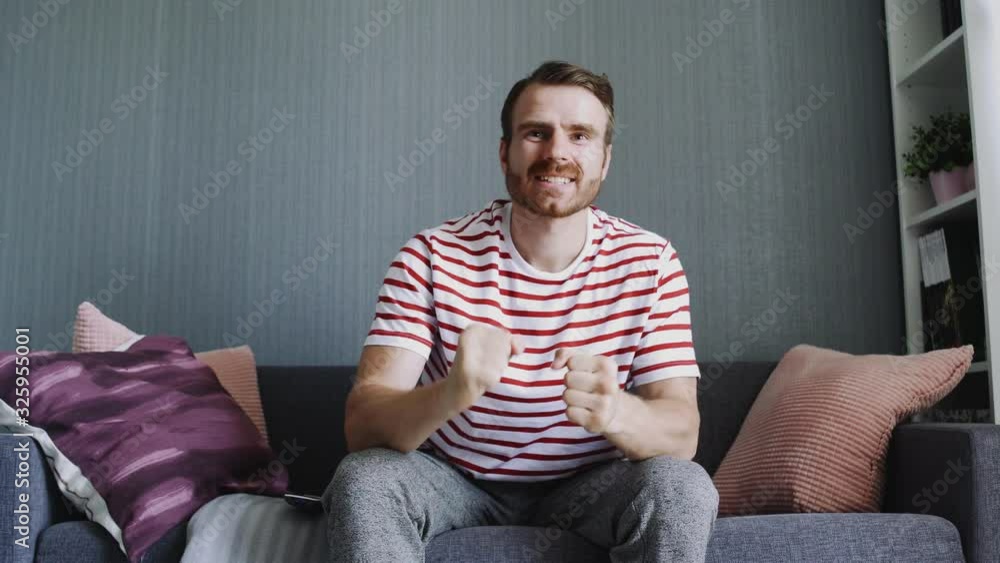 Young man watching a game of sports sitting on the couch Young man watching a game of sports sitting on the couch