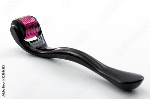 Beauty treatment, mesotherapy or medical collagen production stimulation and micro needling therapy concept titanium pink and black derma roller isolated on white background photo